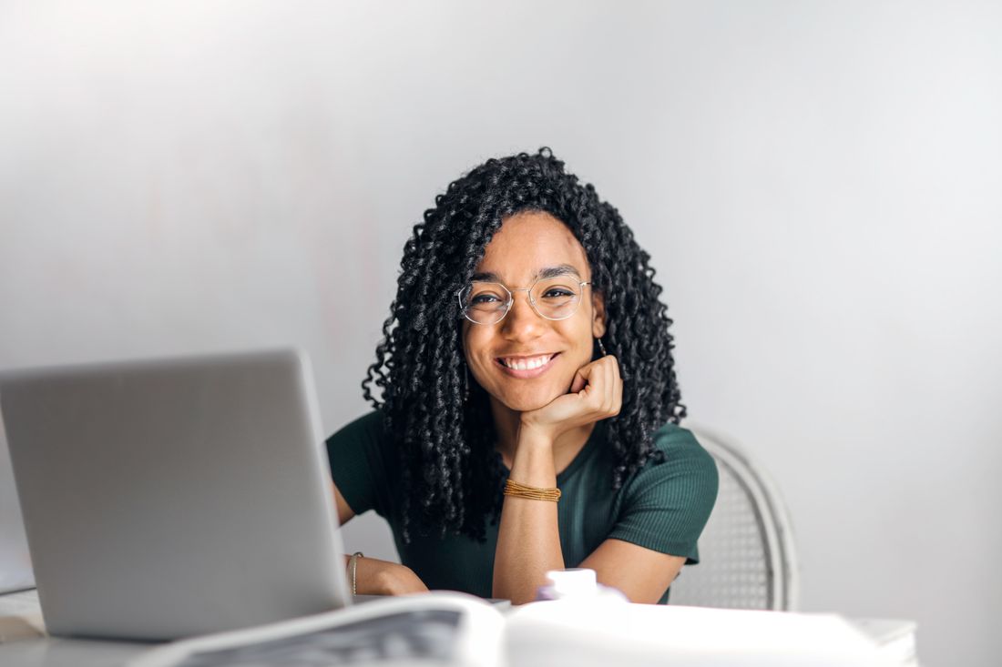 Une femme souriante devant son ordinateur, photographie d’illustration.