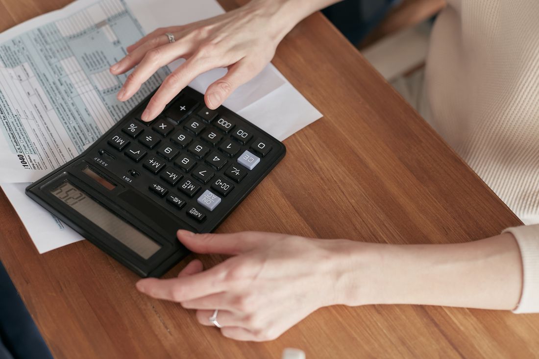 Une personne consulte des documents financiers avec une calculatrice, photographie d’illustration.